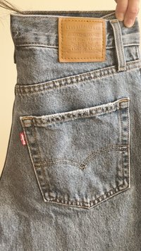 Szürke farmernadrág bőr címkével, amelyen a "Levi Strauss & Co." felirat található a derékrészen, és egy kis piros címke van a hátsó zseben.