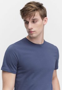 Laivasilmäinen puuvillapaita, jossa on lyhyet hihat, pyöreä kaula-aukko, sileä rakenne ja napakampi malli. Ei näkyviä kuvioita tai yksityiskohtia.