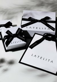 Négy fehér ajándékdoboz fekete szalagbowval, a "LATELITA" márkázásával. Különböző méretek, letisztult, modern dizájn és finom textúrák.