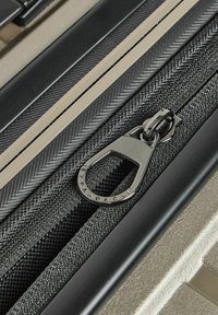 Bagages extensibles au design élégant avec un motif chevrons, des textiles noirs et un matériel métallique pour la durabilité et le style.