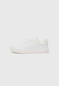 Sneaker bianca con una tomaia sintetica liscia, punta tonda, design con lacci e un logo discreto sul lato. Suola spessa e texture.