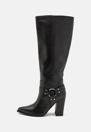 Black leather knee-high boot with a pointed toe, chunky heel, and decorative buckle detail on the ankle strap. Smooth texture, sleek design.