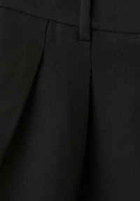 Pantalones negros ajustados que presentan una tela lisa y texturizada con sutiles pliegues y un detalle en la cintura para un ajuste estructurado.
