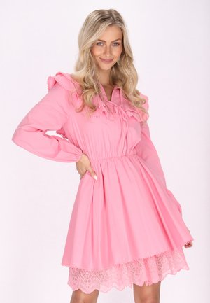 Rochie roz cu mâneci lungi, decolteu cu volane, talie elastică și tiv din dantelă. Material neted cu o siluetă de fustă evazată.
