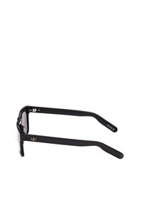 Gafas de sol rectangulares negras con montura gruesa y el logotipo de Adidas en la patilla, colocadas planas sobre un fondo blanco.