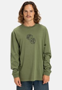 Olive green long-sleeve shirt with a round neckline, featuring black graphic cube designs on the front and logo prints on the sleeves.