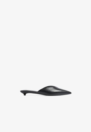 Black leather slip-on shoes with a pointed toe, a low kitten heel, and smooth texture. The design features a clean, minimalistic silhouette.