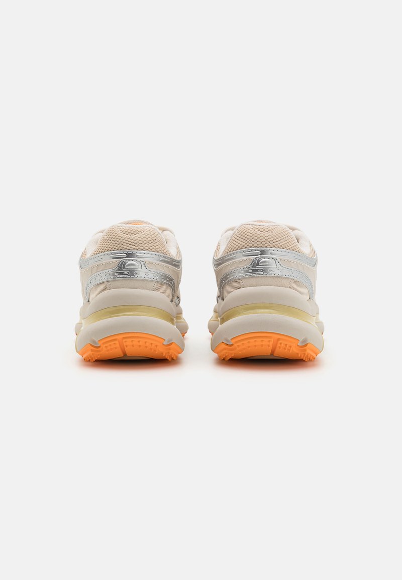 Zapatillas deportivas ligeras con una parte superior de malla beige, detalles en plateado y una suela de goma naranja. Cuentan con una suela acolchada para mayor comodidad.