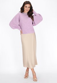 Pulover tricotat lavandă cu sleeve lungi puffate și guler cu mărgele, asortat cu o fustă de satin bej cu fenta pe lateral, purtat cu tocuri aurii.