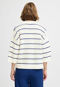 Strikket cremefarvet sweater med blå vandrette striber, korte ærmer og hulmønster detaljer. Ribbet kant og ærmer, afslappet pasform.