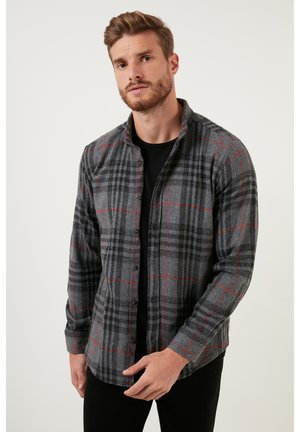 Gray plaid flannel shirt with red accents, button front, and a collar. Long sleeves and relaxed fit, worn over a black T-shirt.