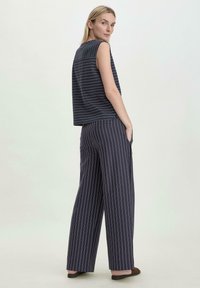 Meriinströkt utan ärmar topp och vida byxor, med vita vertikala ränder, mjukt tyg och avslappnad passform. Minimalistisk design.