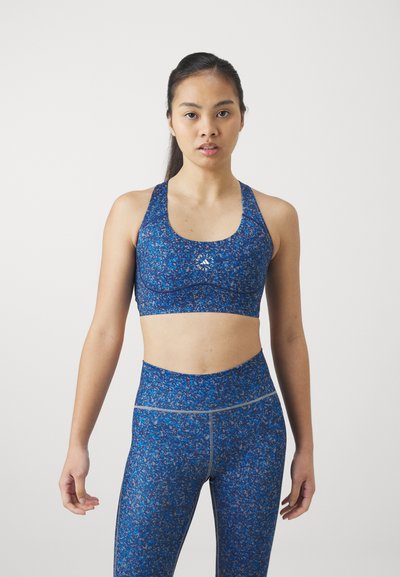 Sujetador deportivo azul y leggings de cintura alta con un patrón floral, fabricados en un tejido elástico con una textura suave y un sutil detalle del logo.