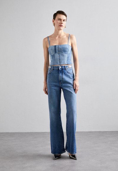 Jeans croppetopp i denim med knapper, med tynne stropper. Kombinert med høyt liv og utsvingte jeans i en lys blå vask. Glitrende detaljer på midjebåndet.