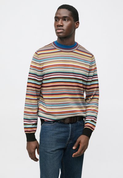 Maglione a righe in maglia con strisce orizzontali multicolori, scollo a coste e polsini neri, abbinato a jeans blu.