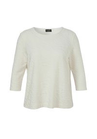 Blouse blanche texturée à manches longues avec un col rond et un ourlet légèrement évasé, présentée sur un fond blanc uni.