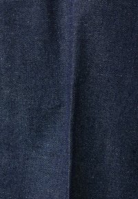 Tissu en denim bleu foncé avec une texture de tissage diagonal visible et une couture verticale centrale traversant le milieu.