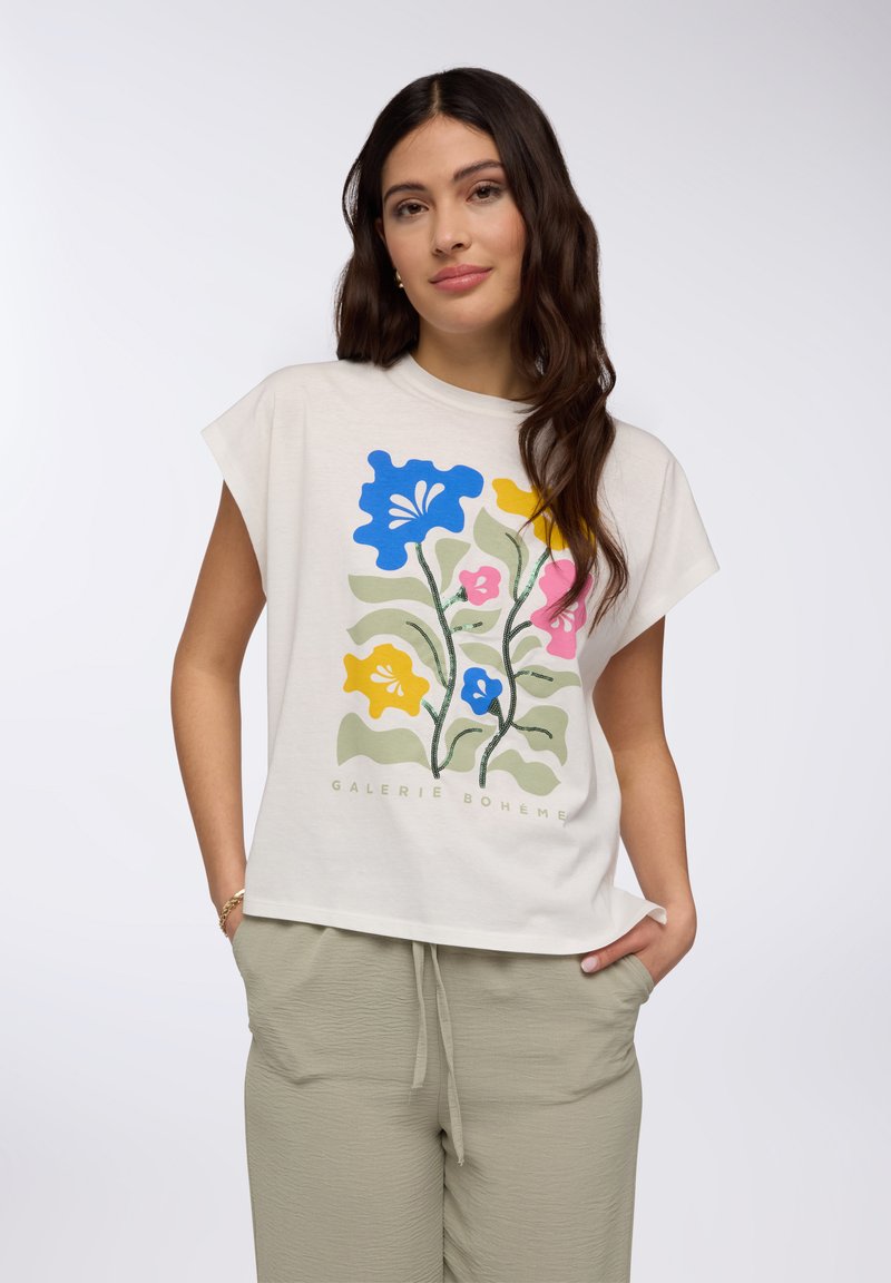 Maglietta a maniche corte color crema con grafica floreale in blu, rosa, giallo e verde. Vestibilità ampia, realizzata in tessuto morbido, con scollatura rotonda.