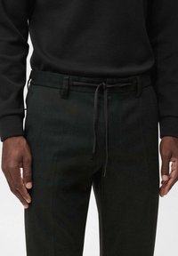 Pantaloni negri dintr-un material texturat, cu un elastic la talie și buzunare laterale. Croieli înguste cu un design curat și minimalist.