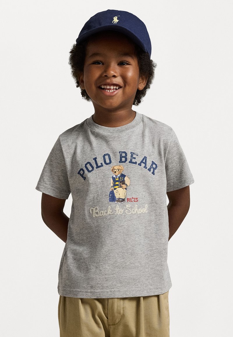 Grå bomull t-skjorte med et bjørnegraphikk i en blå varsityjakke med "Polo Bear" og "Back to School"-tekst i marineblått og hvitt.