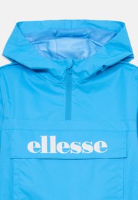 Ryškiai mėlynas gobtuvėmis striukė su priekiniais užtrauktukais ir dideliu kišeniu, ant kurio matomas ryškus baltas "ellesse" logotipas.