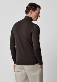 Suéter marrón oscuro con un cuello alto, hecho de material suave. Presenta un diseño ajustado, puños y dobladillo acanalados, visto desde atrás.