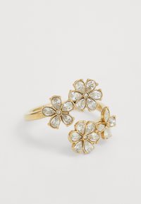 Bague en métal doré ornée de trois motifs floraux, chacun avec des pétales en gemme transparente et une pierre centrale. La bande en métal texturé vient compléter les accents floraux.