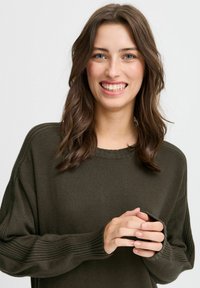 Maglione a coste verde oliva, con accenti a coste e collo rotondo. Presenta maniche ampie e una silhouette rilassata.