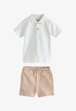 Valkoinen lyhythihainen poolopaita, jossa on kaksi nappia, yhdistetty beigen värisiin, kuminauhavyötäröllisiin ja nyörivarsisiin shortseihin taaperolle.