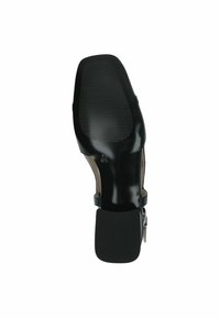 Fekete cipő nyitott kialakítással, texturált talppal, mérsékelt sarkú és csattal díszített pánttal. Simább felület és részletes kidolgozás.