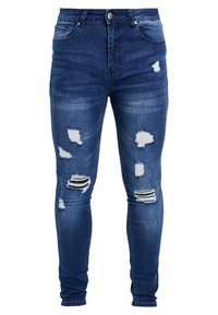 Jeans ajustados en denim azul oscuro con desgastes y parches. Presentan un diseño clásico de cinco bolsillos y un cierre de botón.