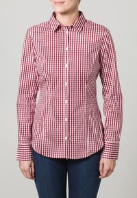 Punainen ja valkoinen ruutupaita, jossa on pitkät hihat, nappisulku, klassinen kaulus ja muotoiltu istuvuus. Valmistettu kevyestä kankaasta.