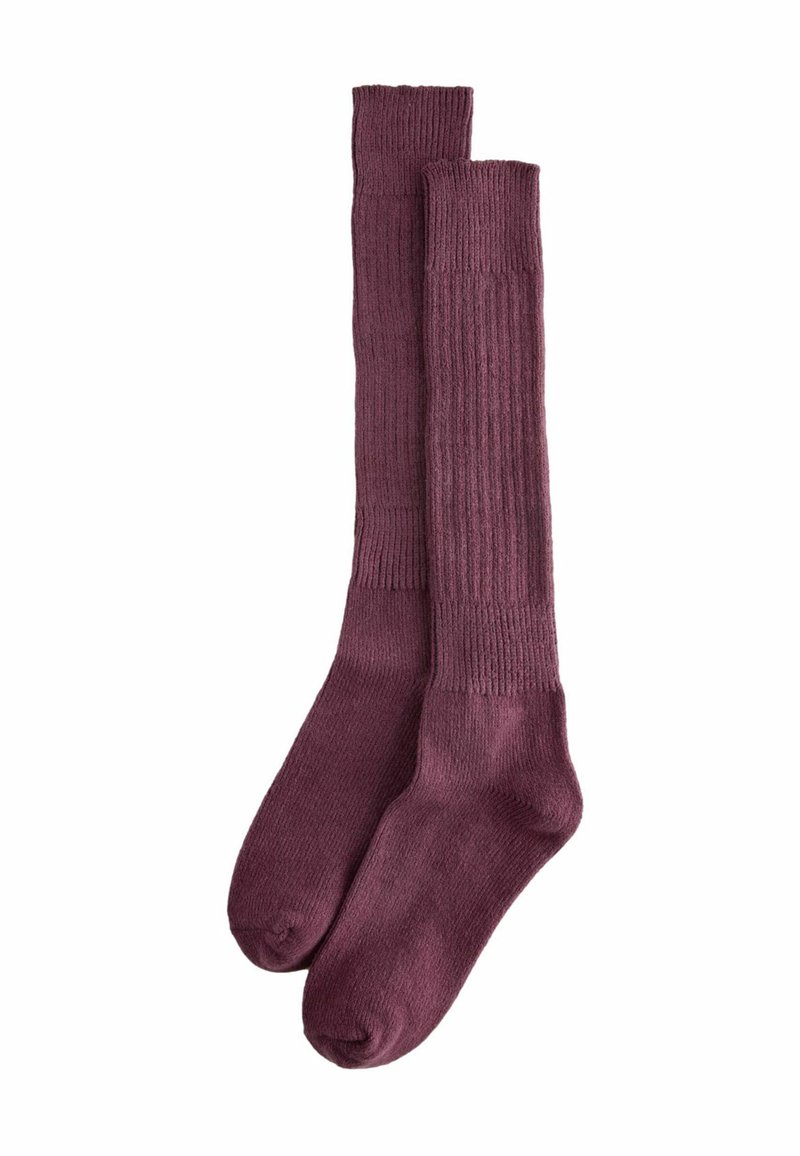 Knähöga strumpor i en djup burgundifärg med ribbad textur. Tillverkade av mjukt material, med förstärkta tån och häl.