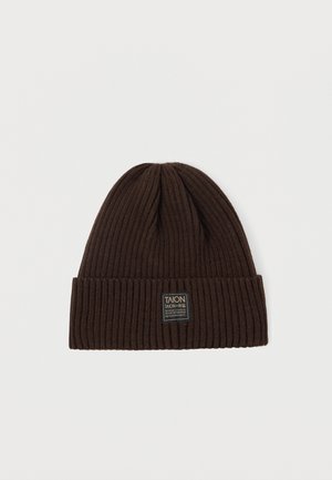 Brown knitted beanie with a ribbed texture, featuring a folded cuff and a rectangular brand label on the front.