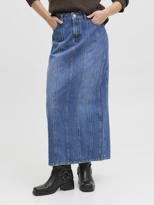 Maxi-Jeansrock mit vertikalen Nähten und Taschen, mit einer taillierten Taille und gerader Silhouette. Schwarze Stiefeletten mit Schnallen.