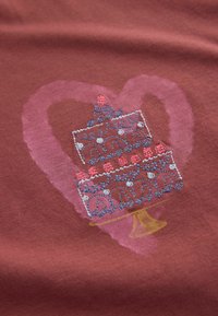 Bordová látka s motívom srdca a grafikou dvojposchodovej torty. Torta je ozdobená modrými a ružovými detailmi, obrysovaná bielou.