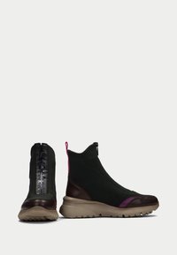 Botas de tobillo elegantes de tela verde oscuro con acentos de cuero marrón, que cuentan con un cierre de cremallera y un detalle morado en el lateral. Suela texturizada.