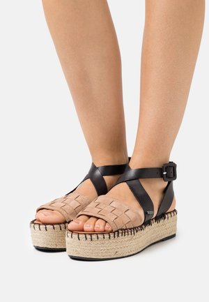 Sandales compensées en suède beige tressé avec des brides en cuir noir, boucle ajustable et détail de semelle en jute tressé.