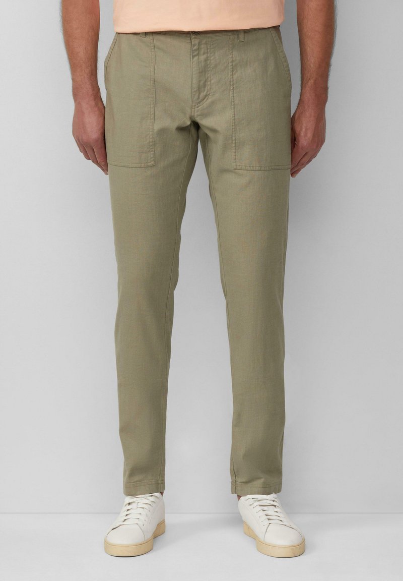 Khaki broek met een rechte pasvorm, voorzakken en zichtbare stiksels, gecombineerd met witte sneakers.