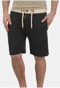 Zwarte shorts van zacht materiaal met een witte trekkoord en een houten knoopdetail op de contrasterende tailleband. Inclusief zijzakken.