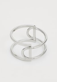 Pulsera de metal plateado en forma de cuff que presenta formas circulares y rectangulares entrelazadas, con un acabado pulido y un diseño abierto para un ajuste ajustable.