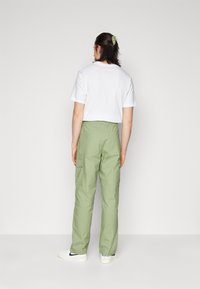 Grønne cargo-bukser med høj talje og løs pasform, parret med en hvid cropped t-shirt. Har lommer og et struktureret hårtilbehør.