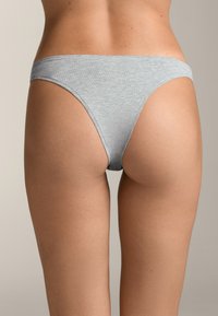 Szürke pamut keverék tanga fehérnemű alacsony derékkal és minimális hátborítással, sima textúrával és tiszta élekkel.