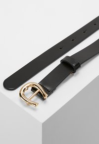 Cinturón de cuero negro con una hebilla curva en tono dorado. Textura suave con un diseño clásico, que cuenta con múltiples agujeros de ajuste.