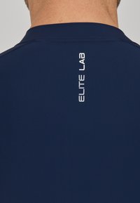 Marinefarbendes Sportshirt mit Rundhalsausschnitt und glatter Textur, mit dem vertikal in Weiß auf der Rückseite aufgedruckten "ELITE LAB"-Logo.