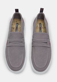 Pantofi slip-on gri din pânză, cu o talpă de cauciuc albă, decorată cu cusături, un accent roșu la călcâi și o branț din plută naturală.
