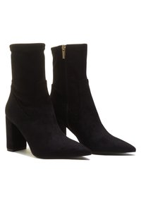 Schwarze Knöchelstiefel aus weichem Wildleder, mit spitzem Zehenbereich, einem seitlichen Reißverschluss und einem robusten Blockabsatz. Glatte Textur mit minimalen Details.