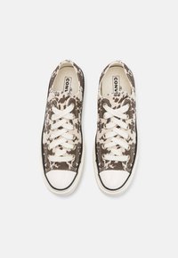 Baskets en toile marron et beige avec un motif marbré, dotées de lacets blancs, d'un embout en caoutchouc et de garnitures noires.