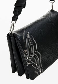 Black leather handbag with a textured finish, detailed white stitching, and decorative leaf patterns. Features a detachable strap and silver hardware.