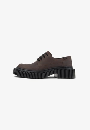 Chaussure marron à lacets avec une semelle noire épaisse, présentant une finition lisse et des détails de couture minimaux. La vue de côté met en valeur son design moderne.